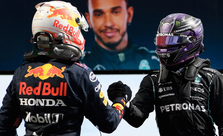 A silver Mercedes Formula 1 car leading under the lights at the Bahrain International Circuit ahead of a Red Bull Racing car during the 2026 season opener.