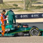 Aston Martin Formula 1 car in the pit lane amid performance struggles, highlighting Honda partnership plans and upcoming 2026 regulation changes.